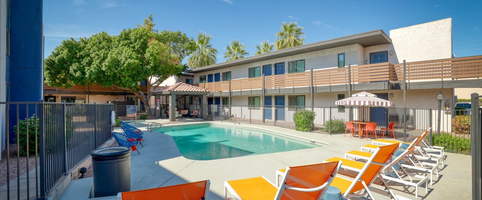 a pool and lounge chairs in front of an apartment building at The Senara