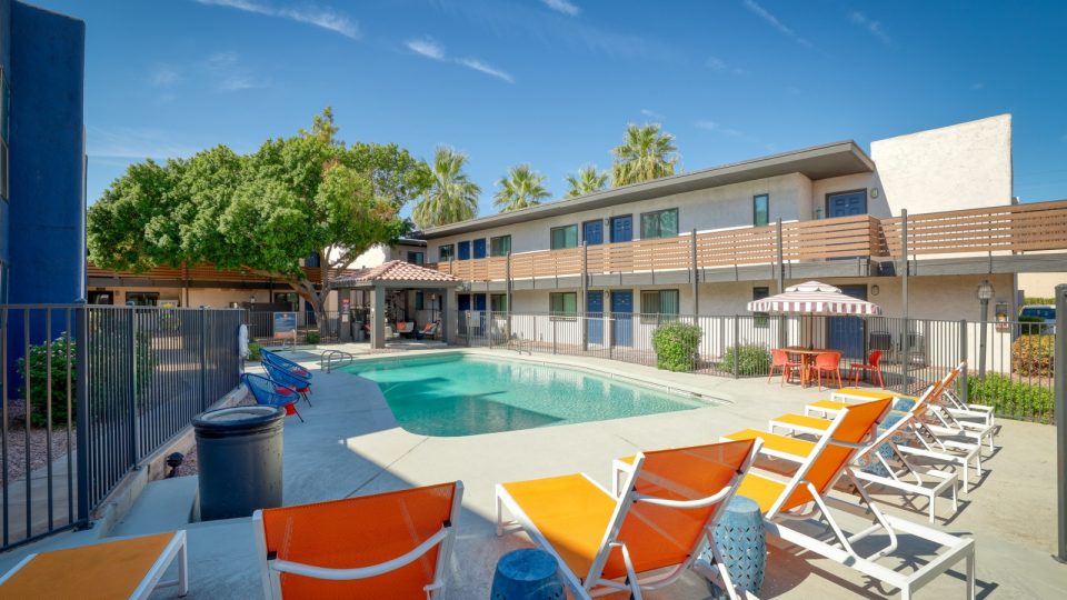 a pool and lounge chairs in front of an apartment building at The Senara